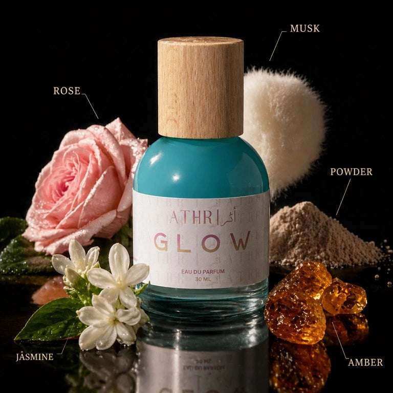 Bottle of Athr Glow perfume with floral elements and labeled ingredients on a dark background