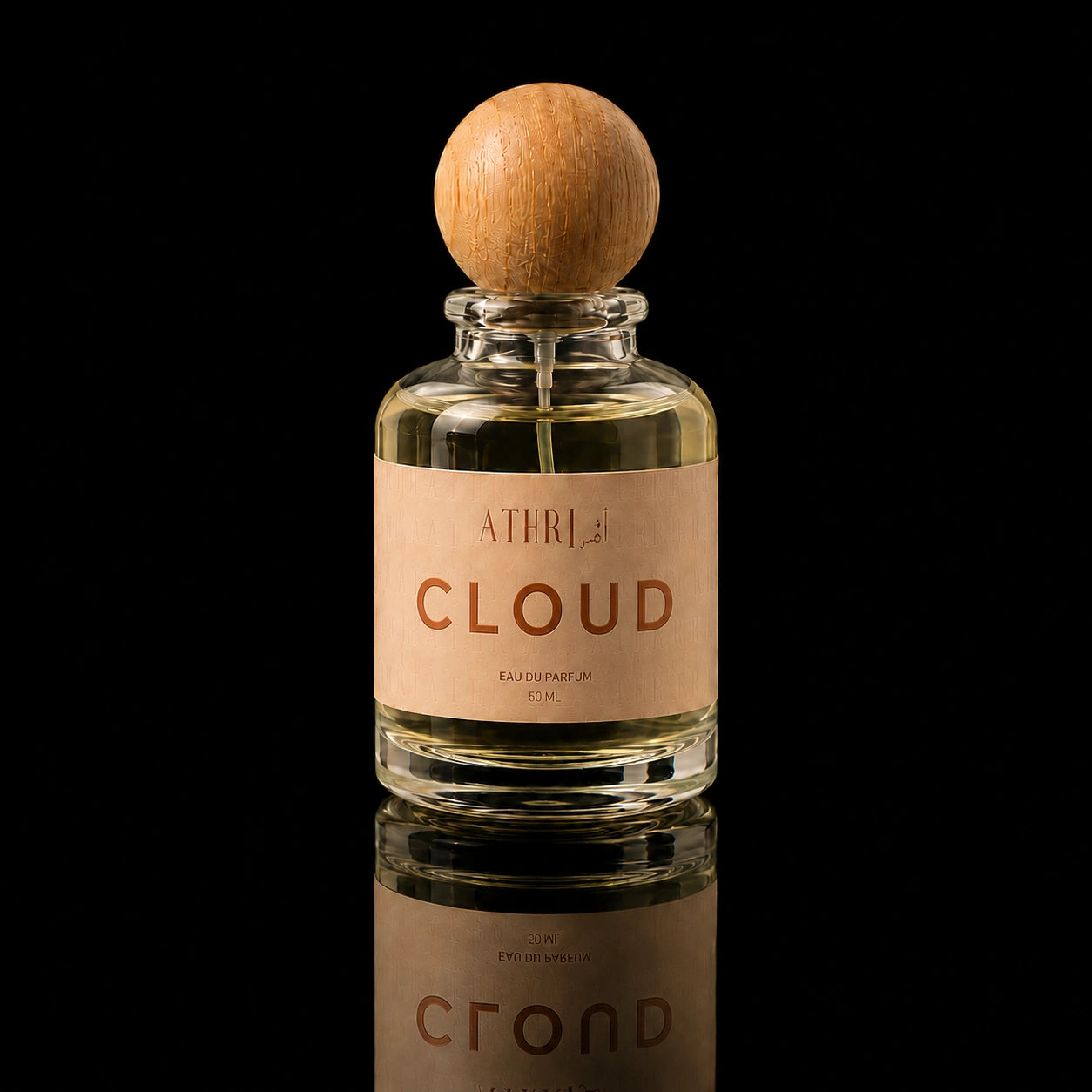 A clear glass perfume bottle with a round wooden stopper and a beige label reading 'ATHRISE BLOOM', centered on a black reflective background.