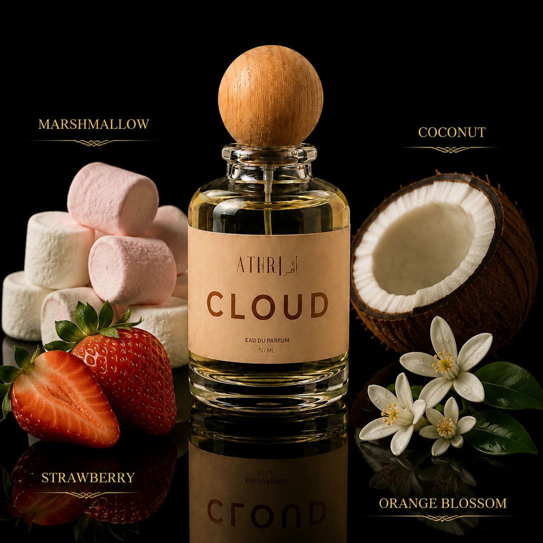 A bottle of Atrium Cloud Eau de Parfum centered on a black reflective background, surrounded by flavor-themed props: marshmallows, a strawberry, a coconut half, orange blossom flowers, and the words Marshmallow, Coconut, Strawberry, and Orange Blossom.