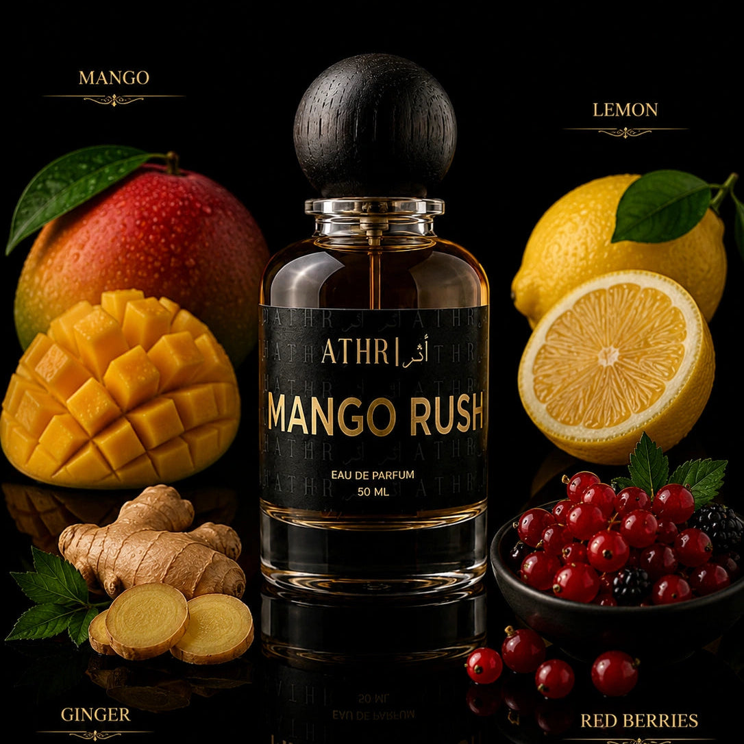 A bottle of ATHRL Mango Rush Eau de Parfum centered on a black reflective surface, surrounded by fresh mango, lemon, ginger, and red berries with labeled text above and below.