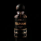 A 50 ml bottle of Athiri Tsunami Eau de Parfum with a black label and a dark wooden cap, set against a solid black background with a subtle reflection below.