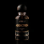 A 50 ml bottle of Athiri addiction Eau de Parfum with a black label and a dark wooden cap, set against a solid black background with a subtle reflection below.