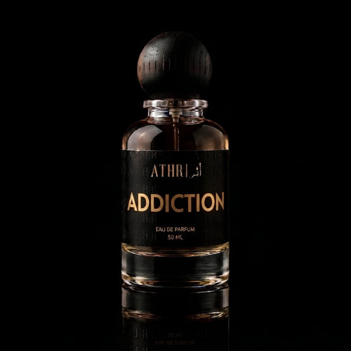 A 50 ml bottle of Athiri addiction Eau de Parfum with a black label and a dark wooden cap, set against a solid black background with a subtle reflection below.