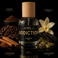 Athr Addiction perfume bottle with coffee beans, vanilla flower, cinnamon sticks, and cardamom on a dark background.