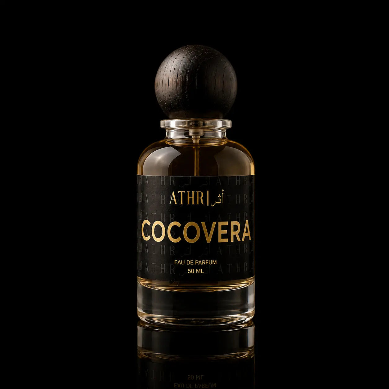 A 50 ml bottle of Athri Cocoverera Eau de Parfum, featuring a clear glass bottle filled with amber-colored fragrance liquid, a black label with gold lettering, and a dark wooden spherical cap, set against a solid black background with a subtle reflection below.