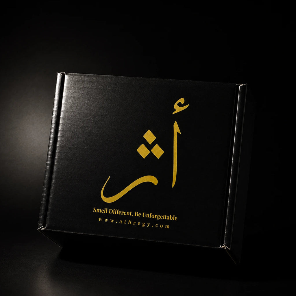 A black rectangular product box with gold Arabic calligraphy and the text 'Smell Different, Be Unforgettable' and 'www.athregy.