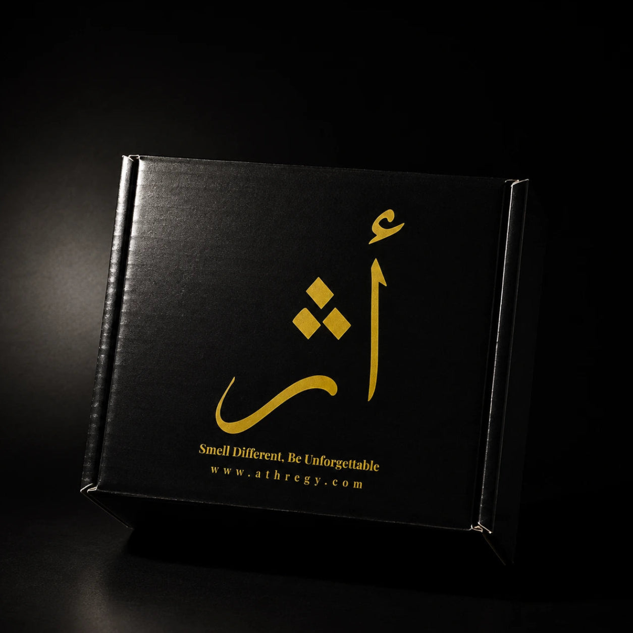A black rectangular product box with gold Arabic calligraphy and the text 'Smell Different, Be Unforgettable' and 'www.athregy.