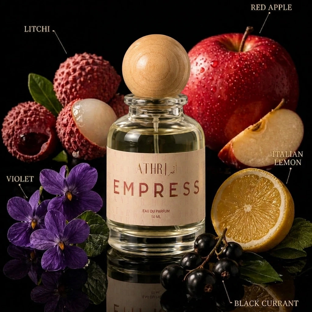 A clear glass perfume bottle with a round wooden stopper and a beige label reading 'ATHRI EMPRESS' is centered against a black background, surrounded by fragrance notes labeled Litchi, Red Apple, Violet, Italian Lemon, and Black Currant.