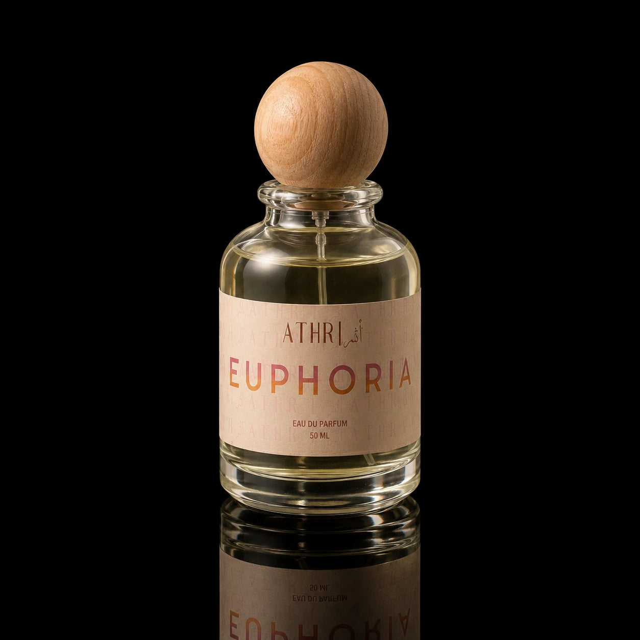 A clear glass perfume bottle with a light wood spherical cap, filled with pale golden liquid. The bottle has a beige label with the brand name 'ATHRI' and the scent name 'EUPHORIA' in gold and pink lettering.