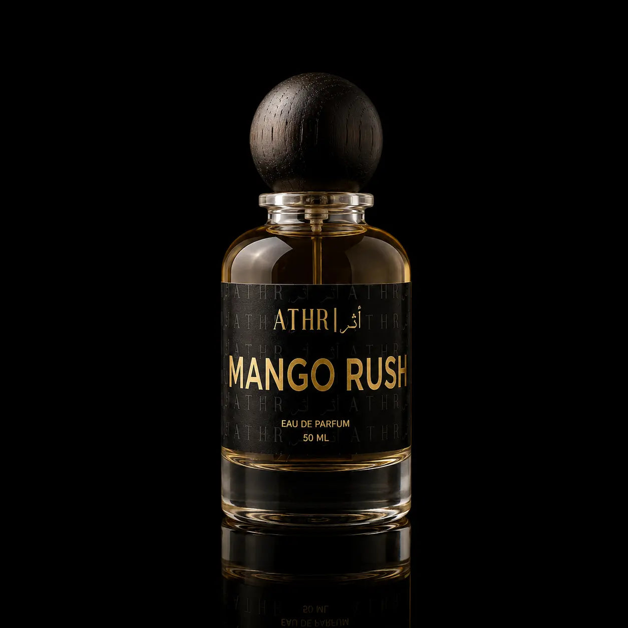 A 50 ml bottle of Athri Mango Rush Eau de Parfum, featuring a clear glass bottle filled with amber-colored fragrance liquid, a black label with gold lettering, and a dark wooden spherical cap, set against a solid black background with a subtle reflection below.