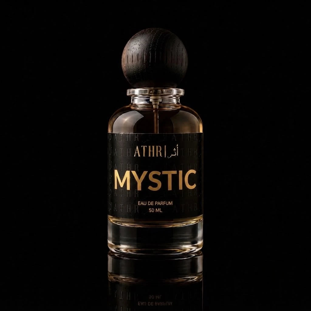 A 50 ml bottle of ATHRI MYSTIC Eau de Parfum with a dark wooden spherical cap and a black label featuring gold lettering, set against a solid black background with a subtle reflection below.