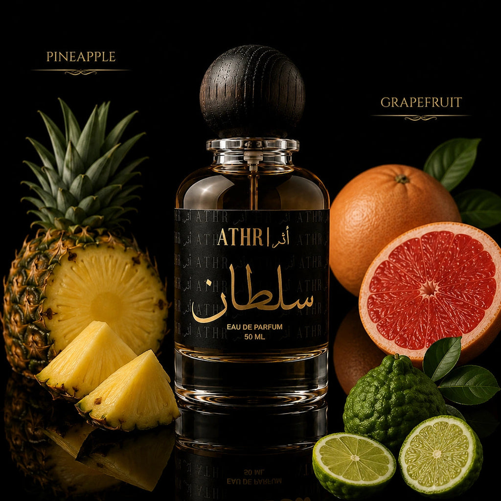 A bottle of ATHRI سلطان Eau de Parfum centered on a black reflective surface, surrounded by its fruit notes: pineapple, grapefruit, bergamot, and kumquat. The perfume bottle has a dark wood cap and a black label with gold Arabic calligraphy and English text.