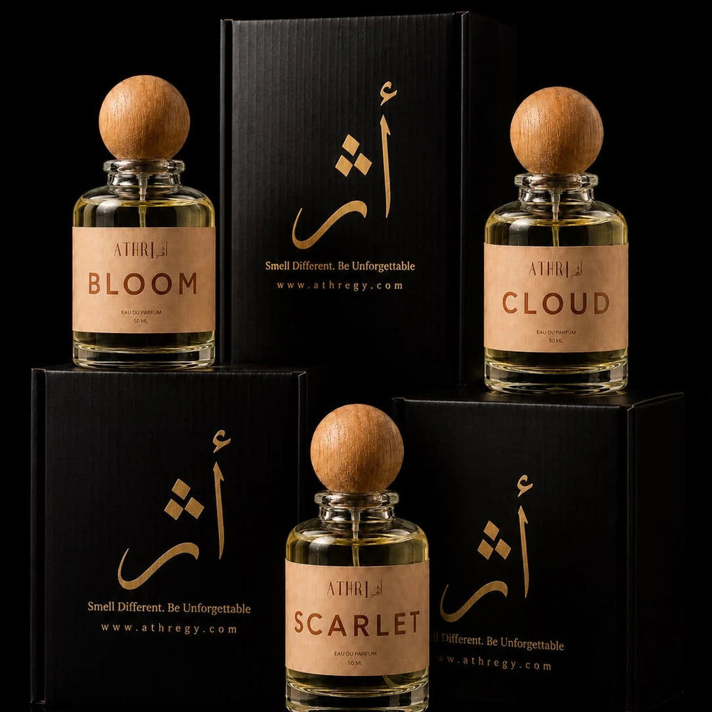 Three perfume bottles with round wooden caps and beige labels are arranged with their black boxes on a black background. The front bottle is labeled SCARLET, the left bottle is labeled BLOOM, and the right bottle is labeled CLOUD.
