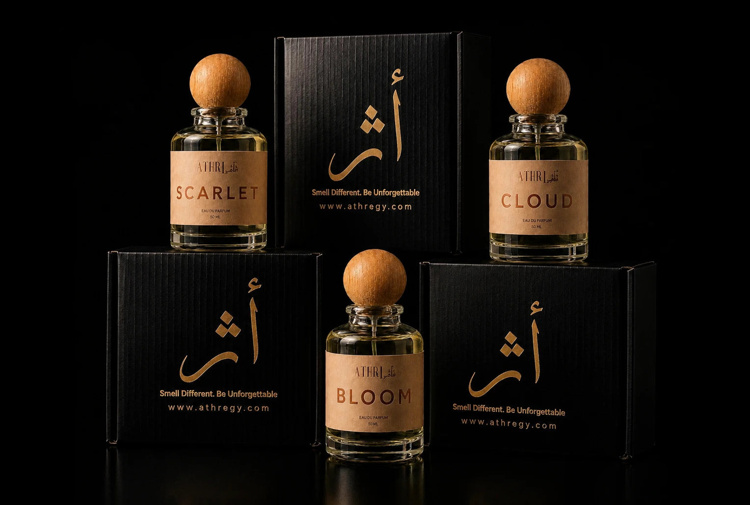 Four bottles of Ahlalih fragrances with black boxes, arranged symmetrically on a black background. The bottles have light wood caps and beige labels with gold lettering, labeled Scarlet, Cloud, Bloom, and Unearthable.